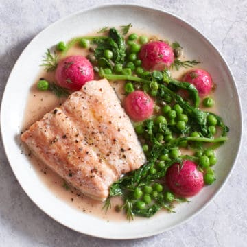 salmon with peas and radishes on a white plate