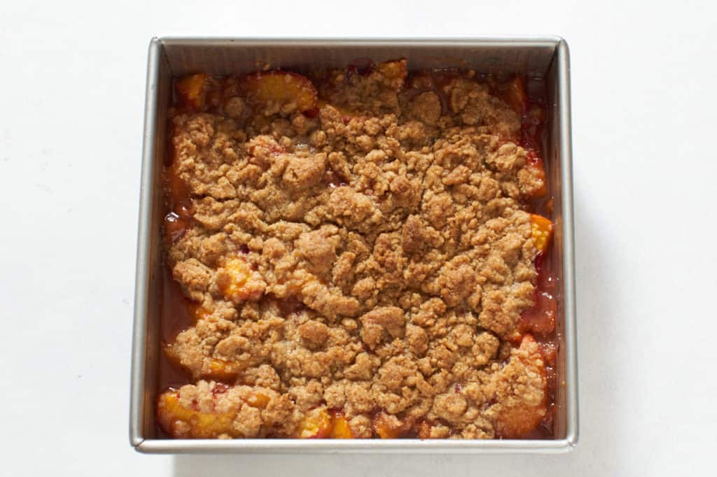 Freshly baked peach crumble in a square pan.