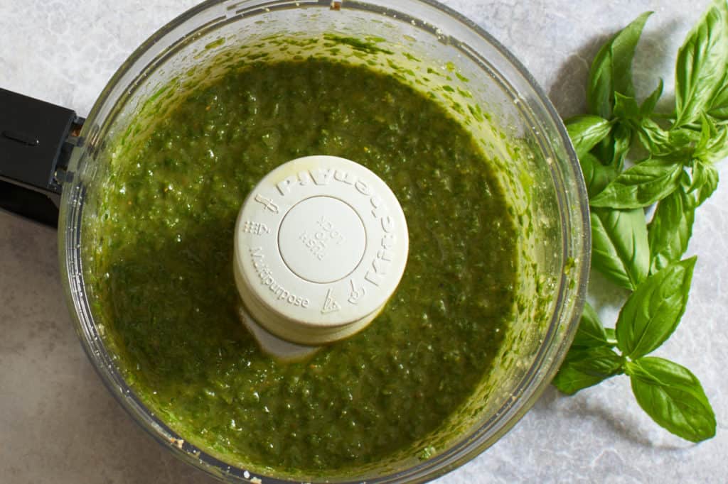 A food processor filled with finished pesto.