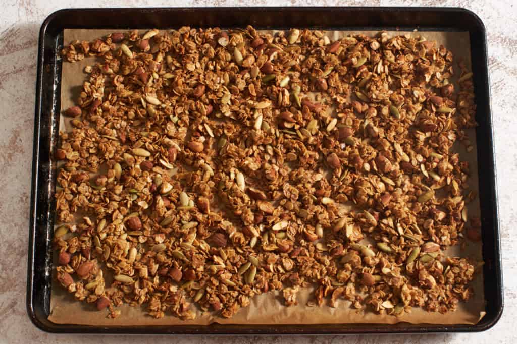 Freshly baked homemade granola on a parchment lined sheet pan.