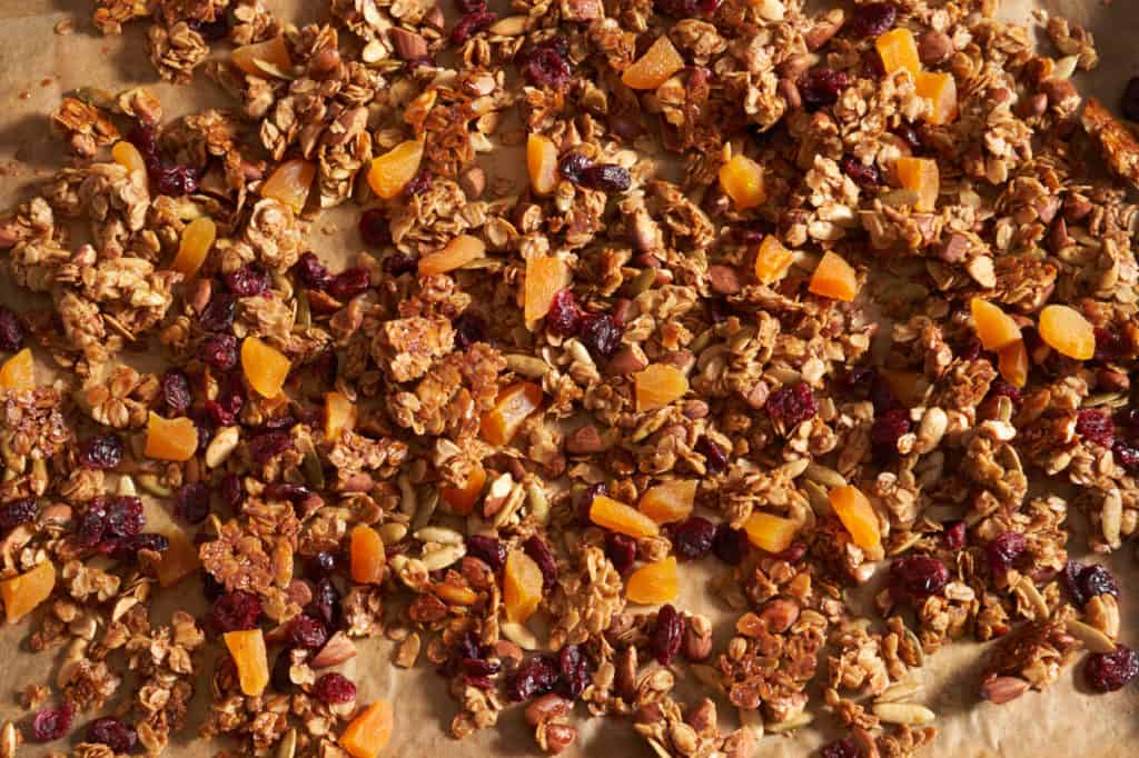 Homemade gluten free granola on a parchment lined sheet pan.