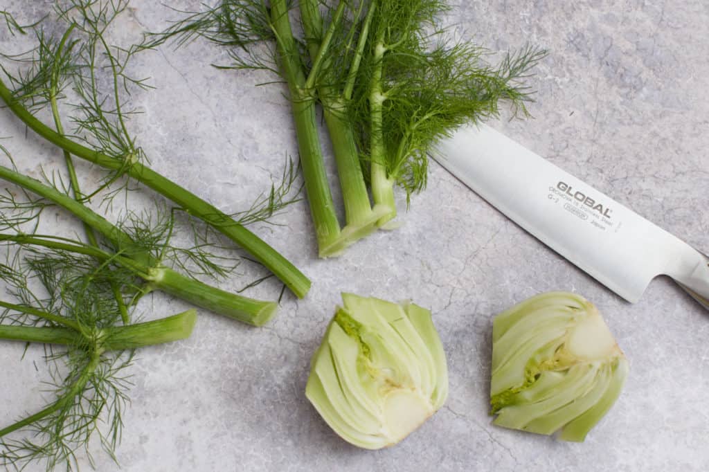 A knife with a fennel bulb and fronds.