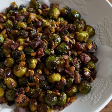 Oven roasted brussels sprouts with pistachios, dates, and lime in a white bowl.