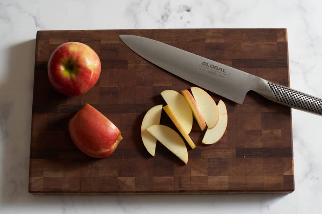 Sliced apples and a knife on a cutting board.