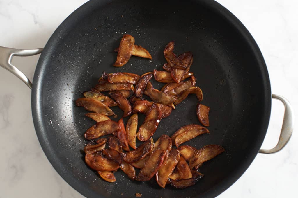 A large skillet with slices of caramelized apples.