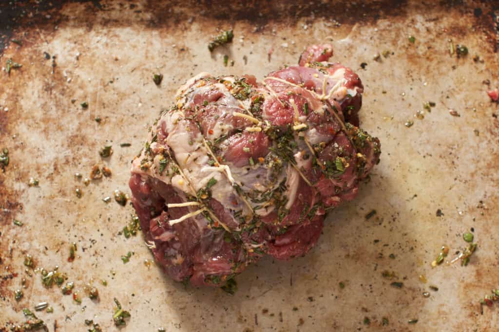 A lamb leg that has been seasoned with herbs, rolled and tied with butcher twine.