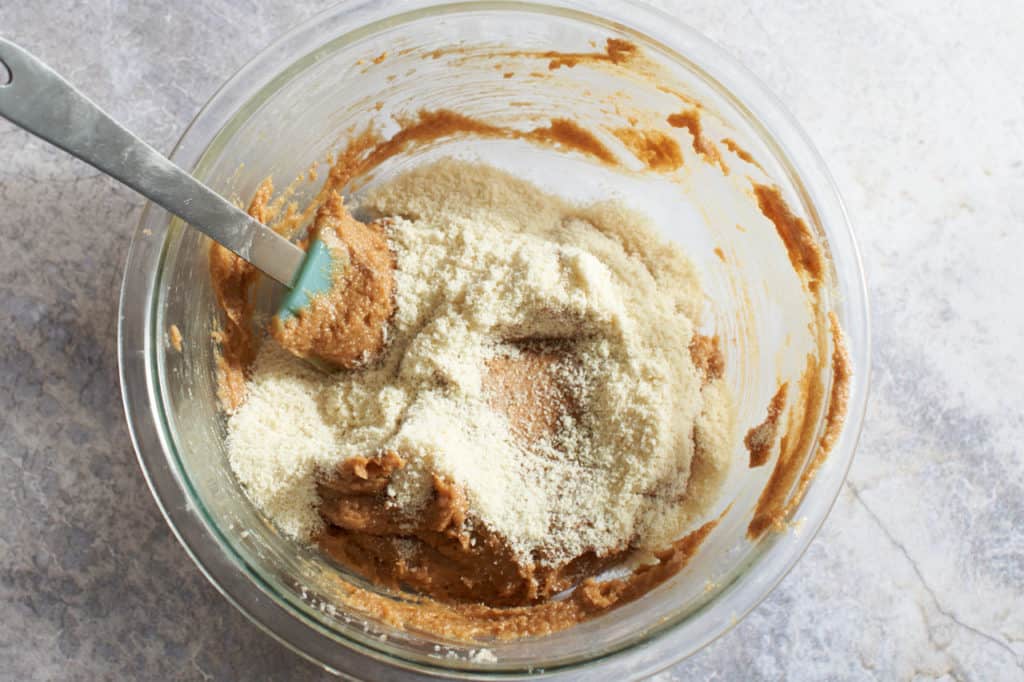 Almond flour added to a bowl of peanut butter cookie batter.