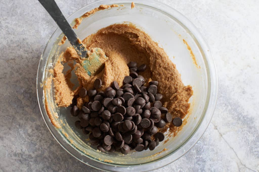 Chocolate chips are added to a bowl of peanut butter cookie batter.
