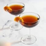 Two hanky panky cocktails in coupe glasses garnished with twists of orange.
