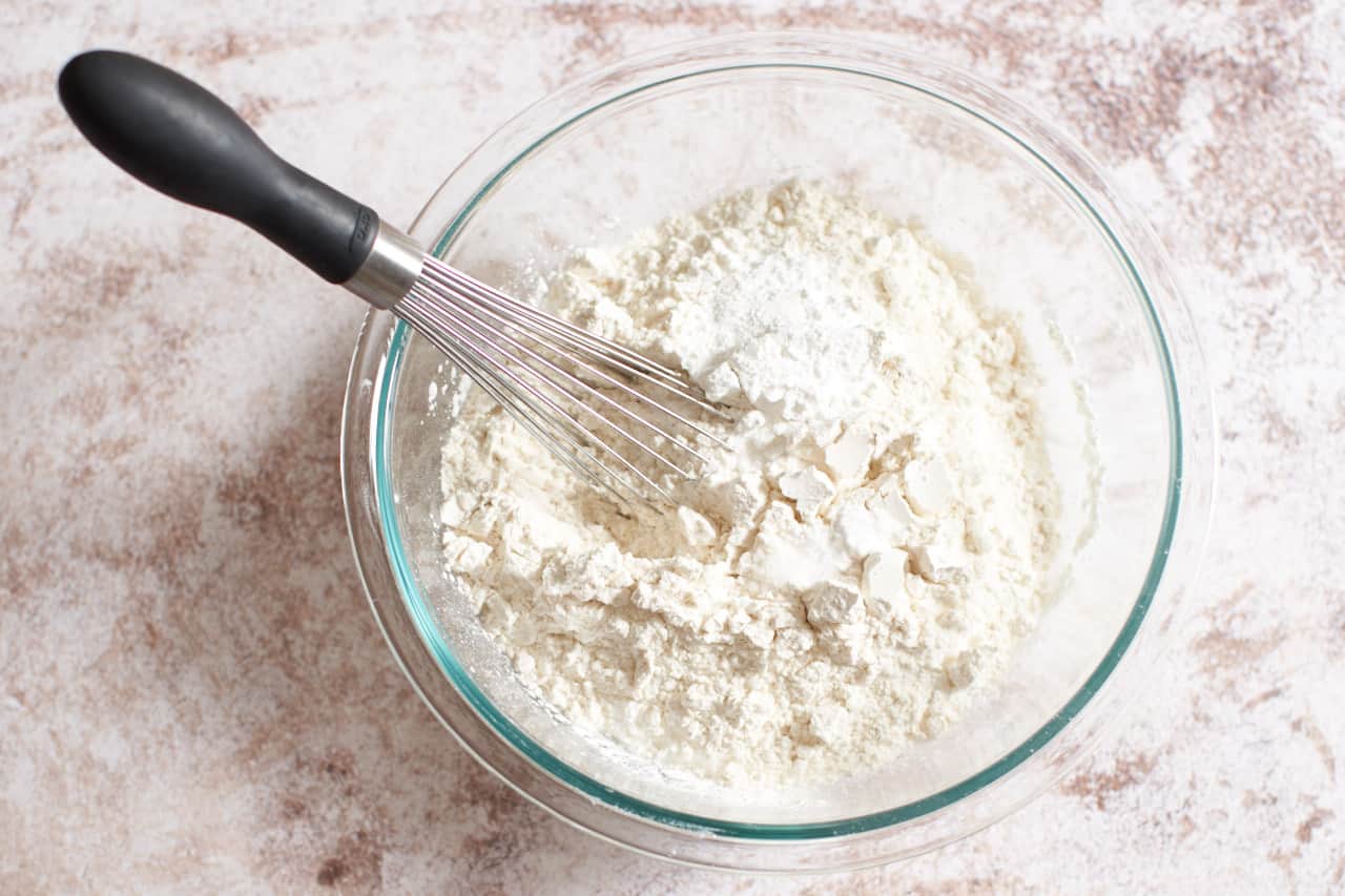 A bowl of dry baking ingredients with a whisk in it.