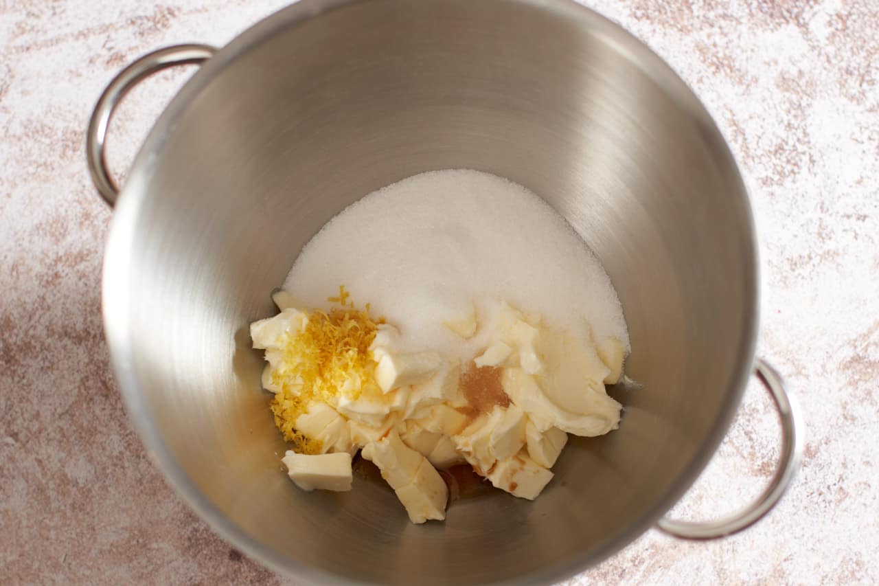 A metal mixing bowl with butter, sugar and lemon zest.