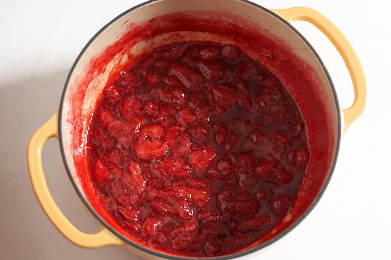 A yellow Dutch oven filled with cooked strawberry compote.