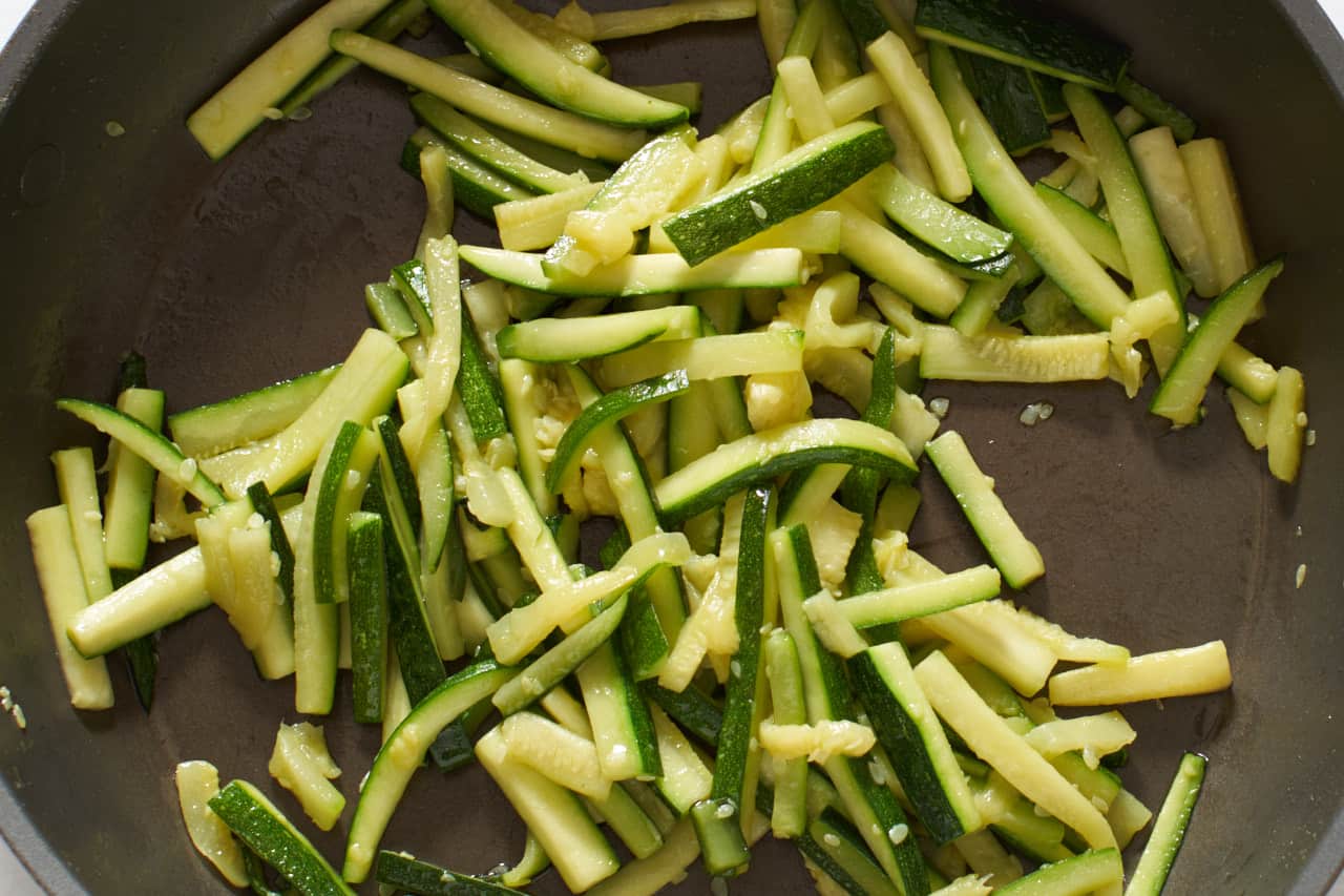 Cooked zucchini batons in a skillet.