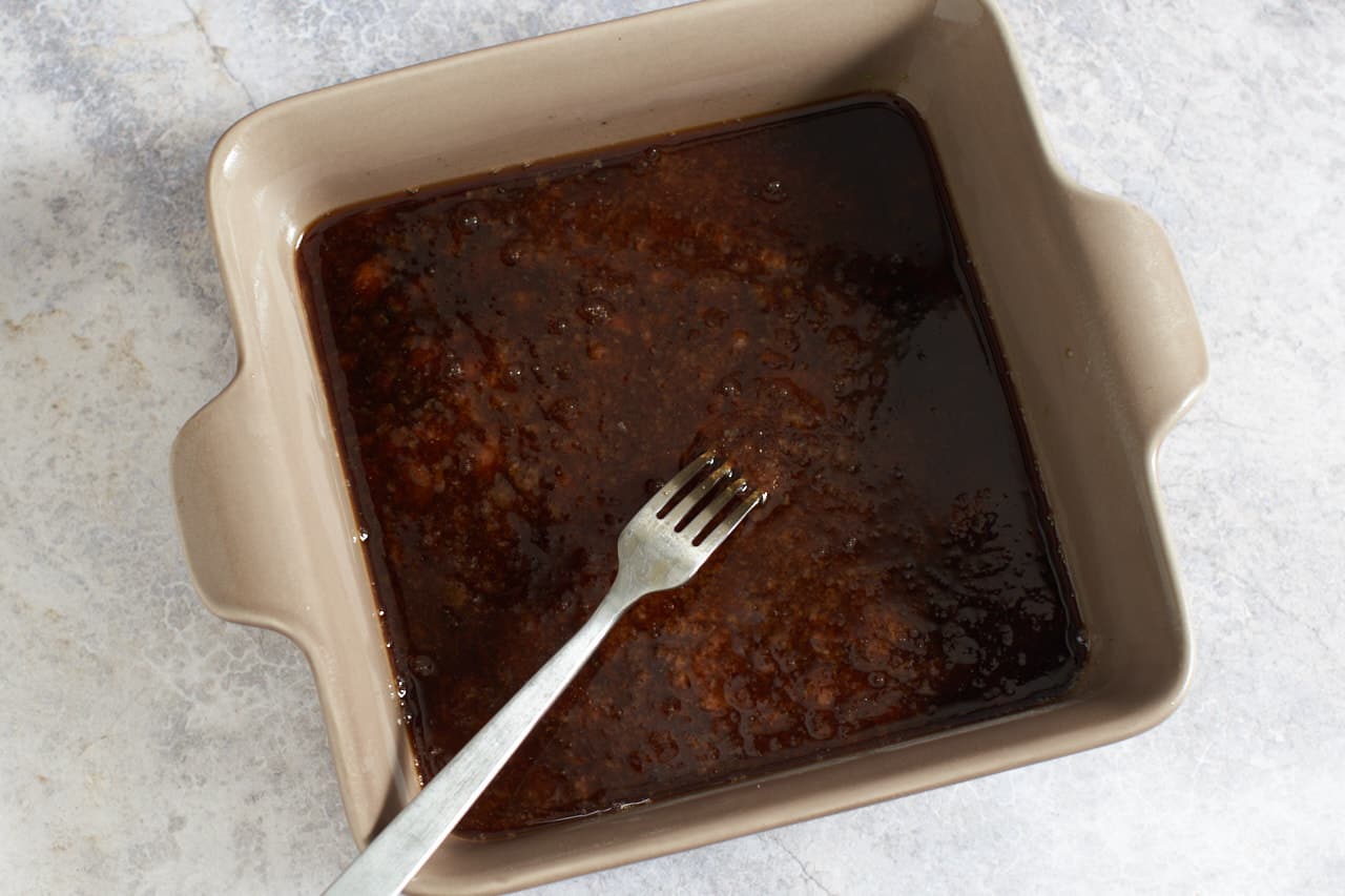 A fork in a brown dish of granita beginning to freeze.