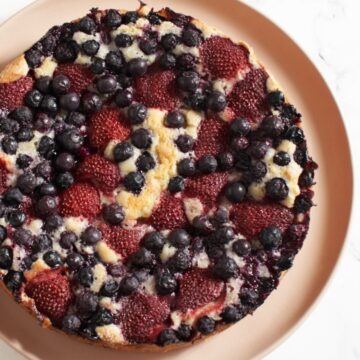 Top down view of a mixed berry cake on a pink plate.