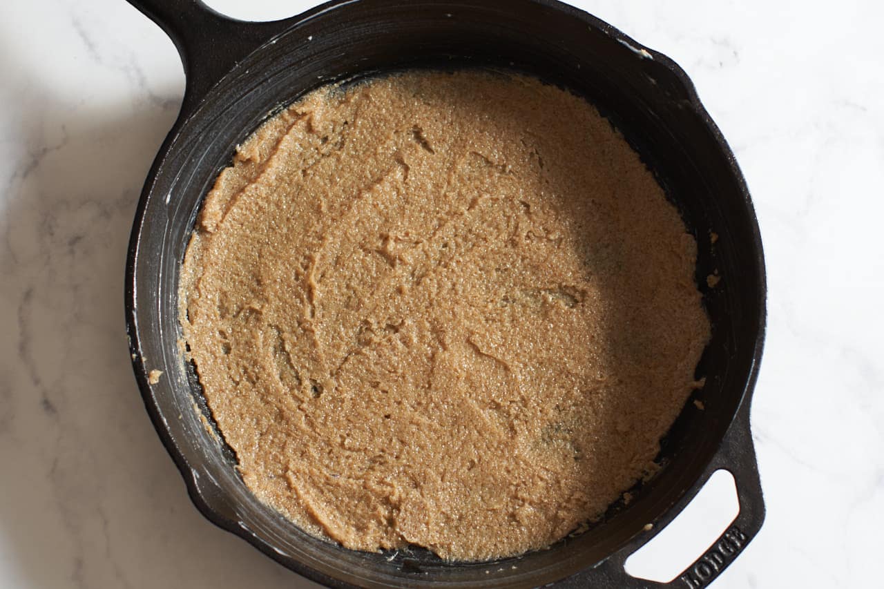 Softened butter and brown sugar spread on the bottom of a cast iron skillet.