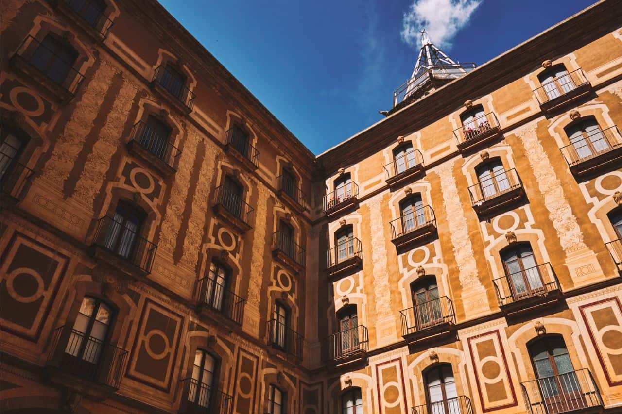 Looking upward toward two buildings with elaborate architectural decoration in a Barcelona courtyard.