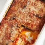 A casserole dish of vegetarian eggplant lasagna with a portion cut out of it.