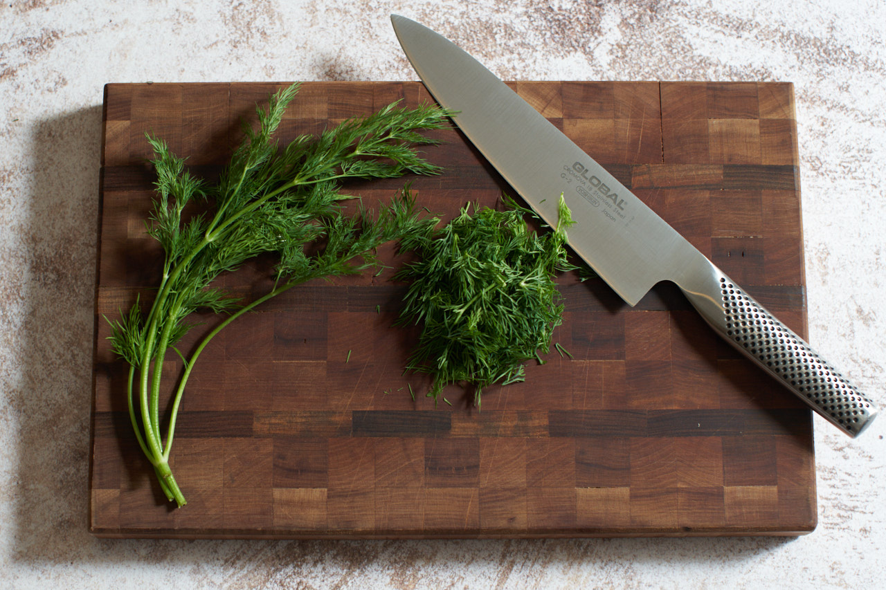 Fresh chopped dill on a cutting board with a knife.