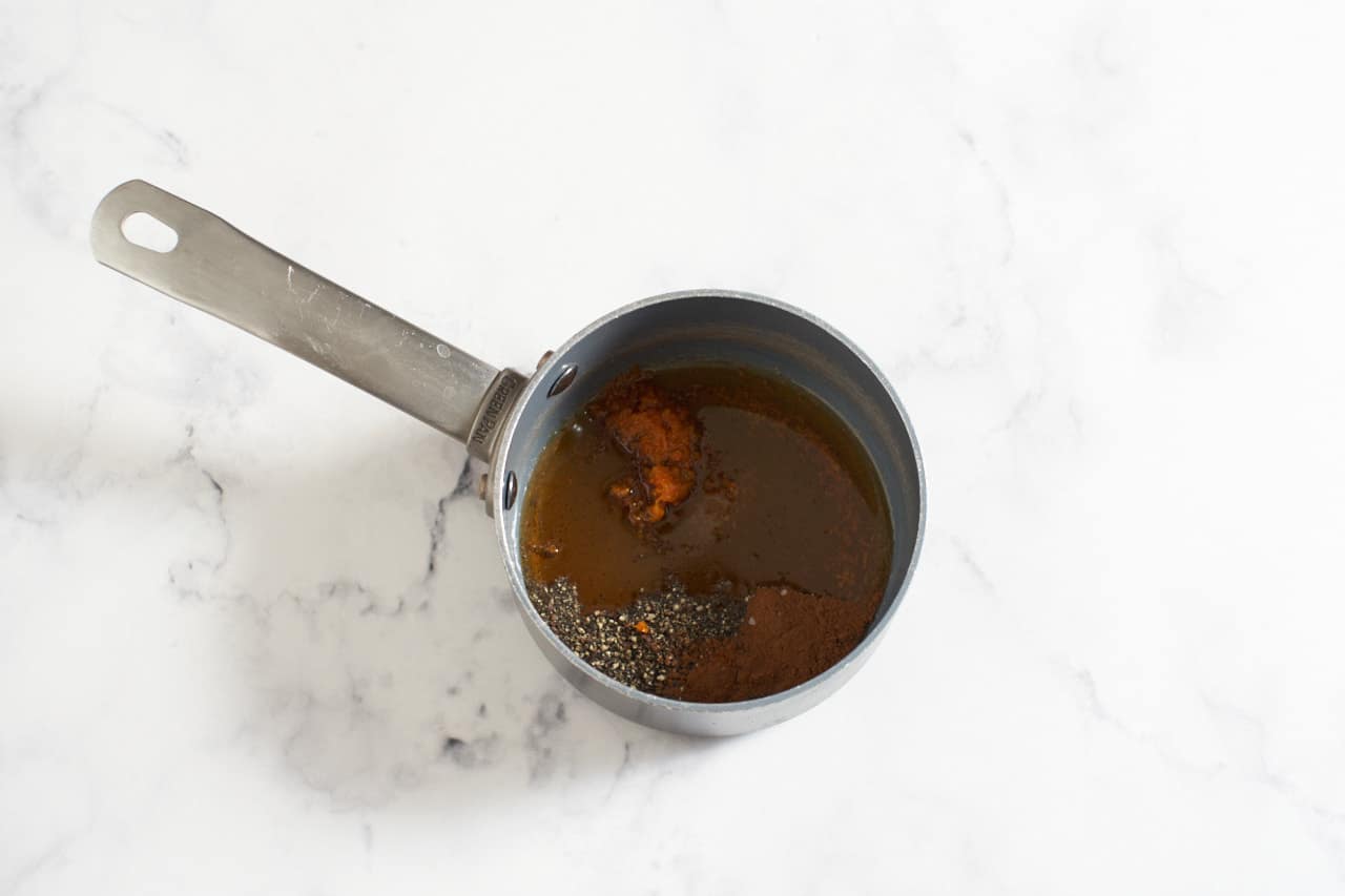 A small sauce pan containing maple syrup and spices.