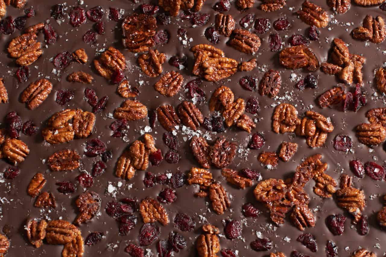 Pecans, cranberries, and sea salt have been added to dark chocolate to make bark.