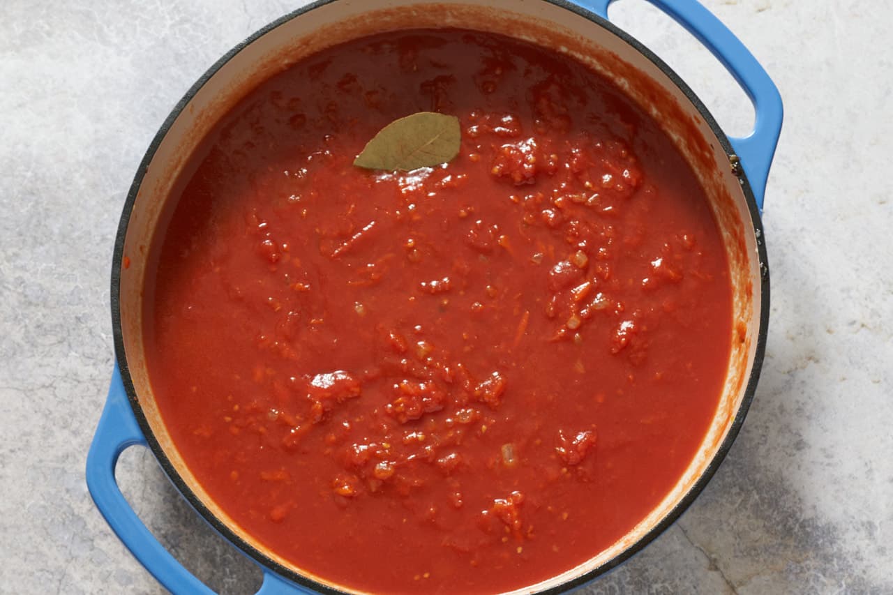 Finished tomato sauce for holubtsi in a blue pan.