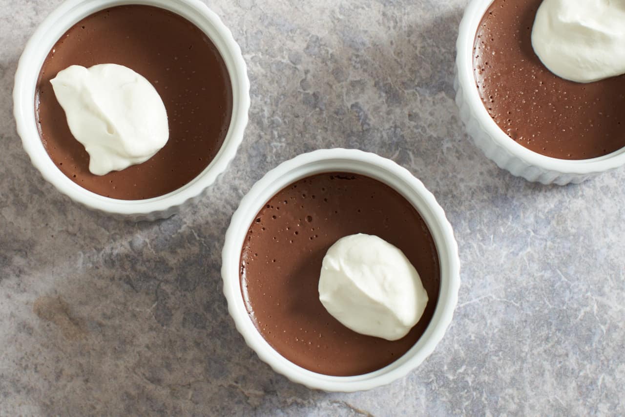 Three chocolate pots de creme topped with whipped cream.