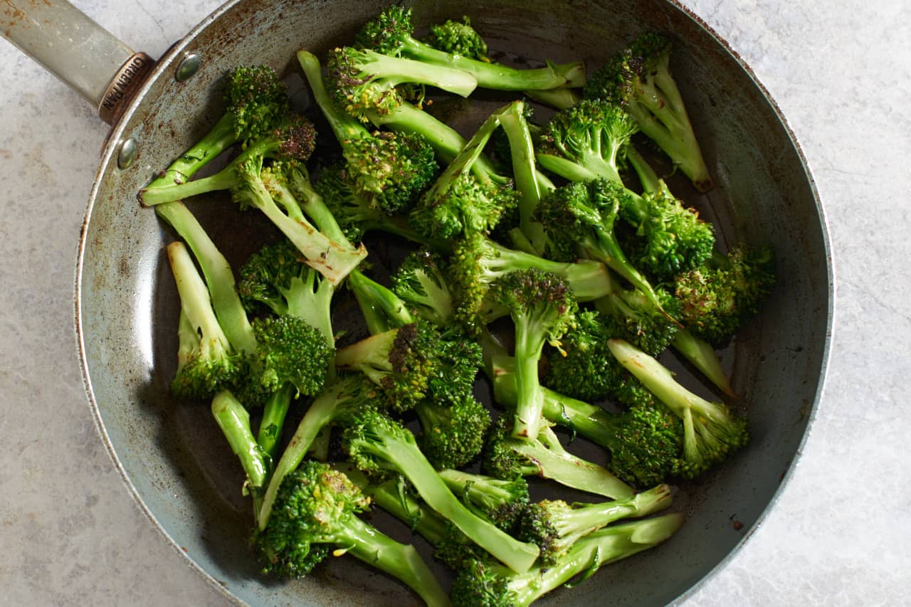 Cooked broccoli stalks with crispy edges in a skillet.