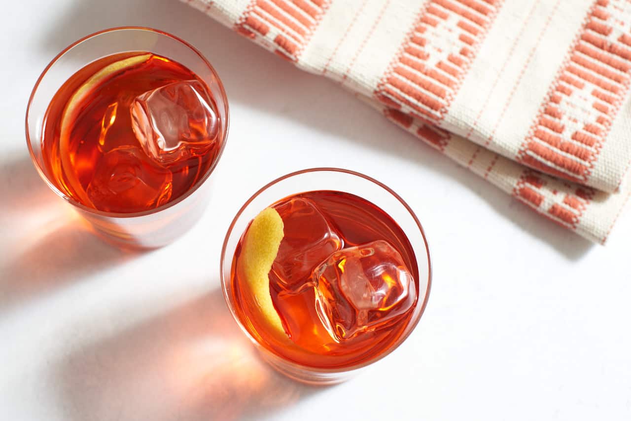 Top down view of two rosita cocktails next to a towel with an orange pattern on it.