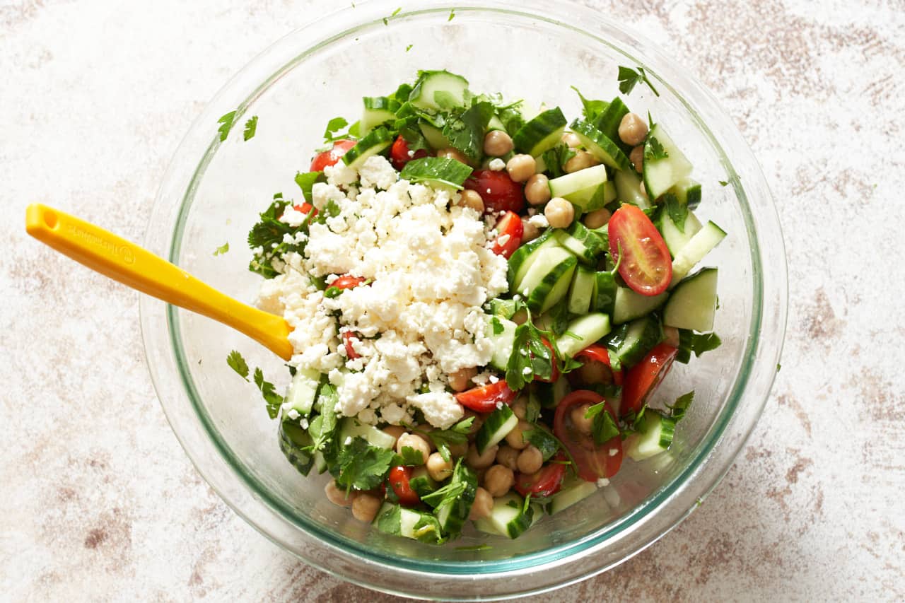 Garbanzo bean salad mixed in a bowl with feta cheese on top.