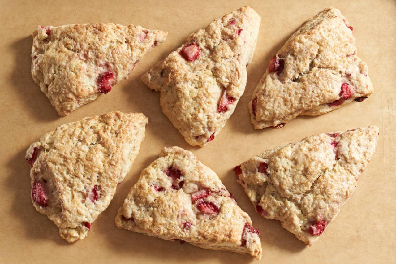 6 strawberry scones arranged on brown parchment paper.