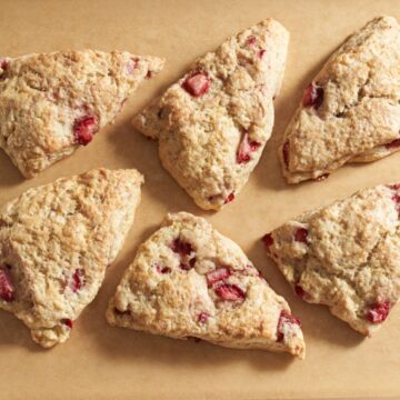 Six strawberry scones on brown parchment paper.
