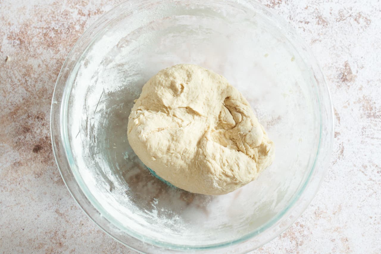 A ball of dough with a rough exterior in a glass bowl.