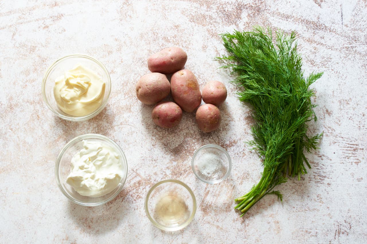 Red potatoes, fresh dill, and small glass bowls of sour cream, mayonnaise, salt and cider vinegar.