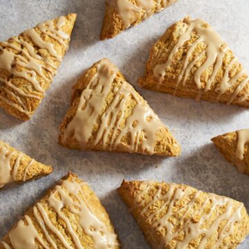 Pumpkin scones with maple glaze on a gray surface.