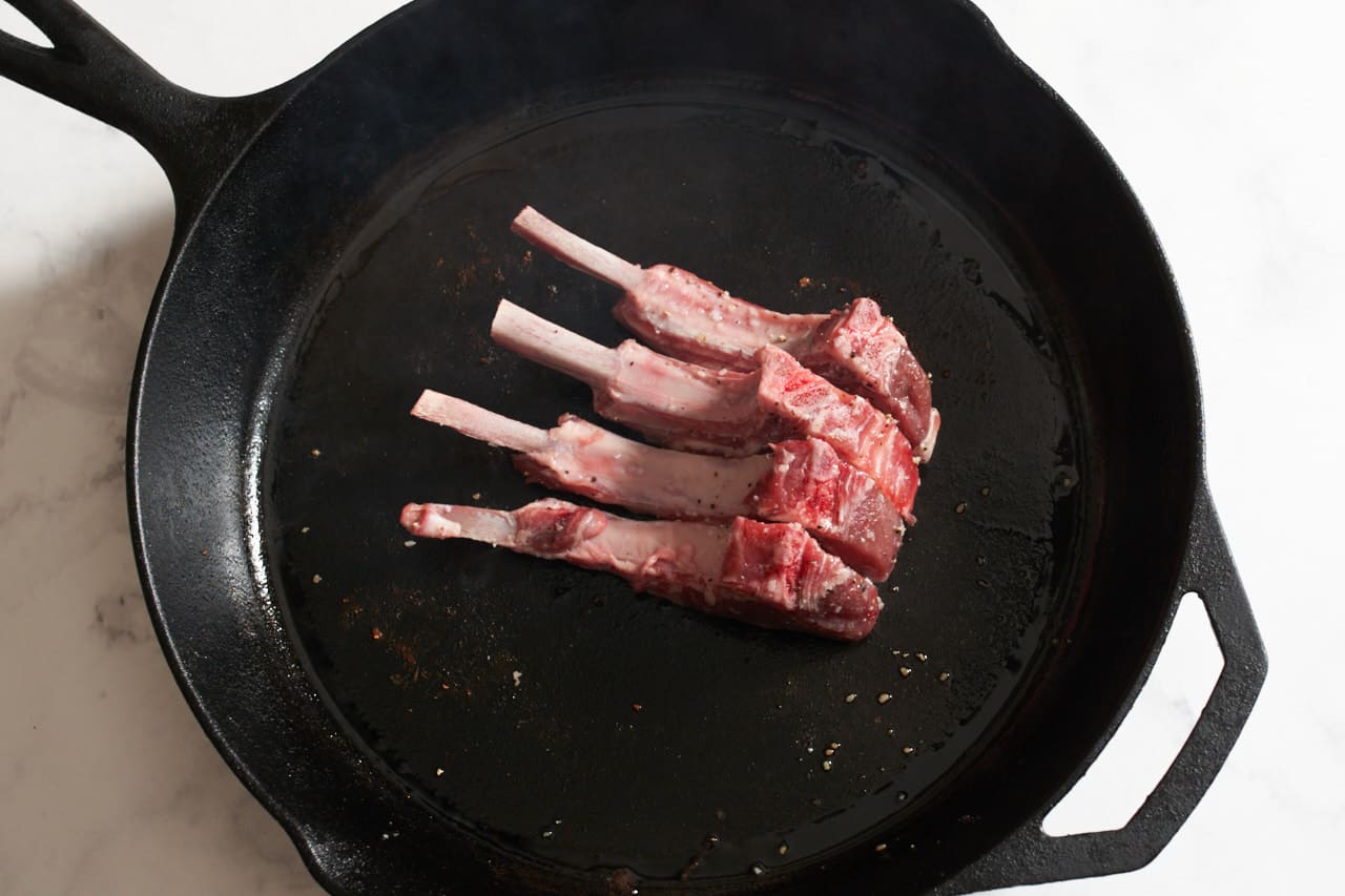 Lamb chops in a cast iron skillet placed on their side to render the fat.