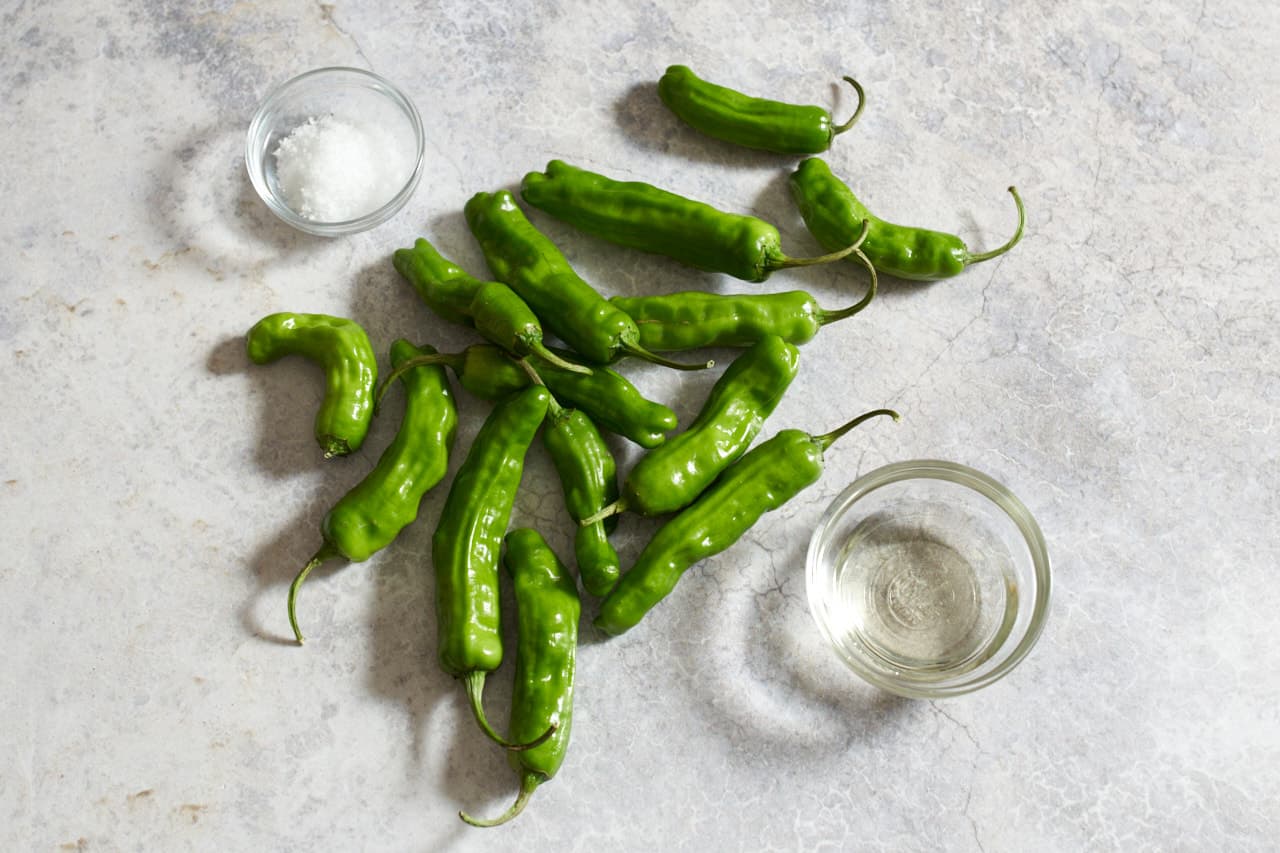 Shishito peppers and two small bowls of sunflower oil and salt.