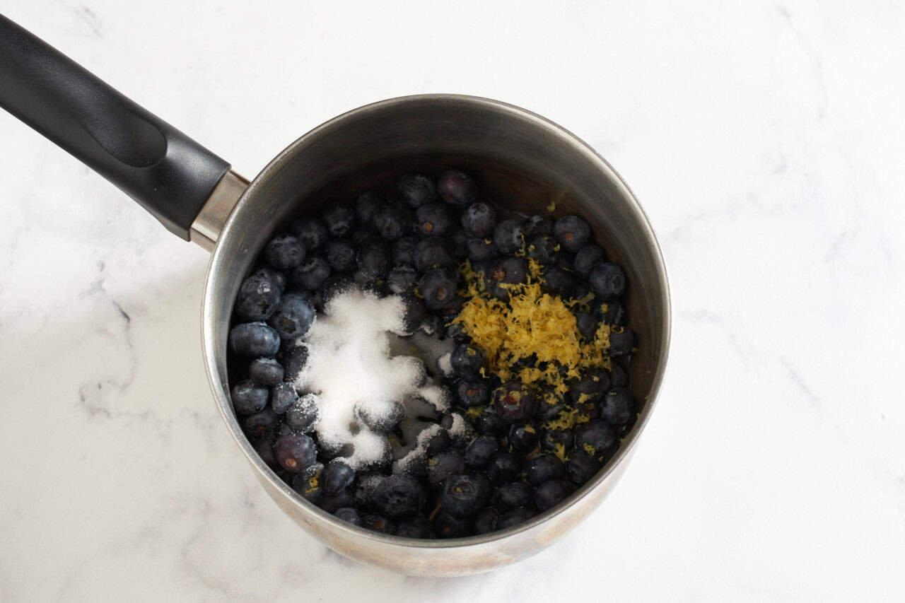 A saucepan with blueberries, sugar, and lemon zest.