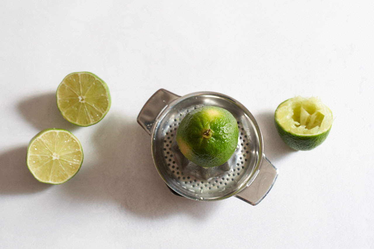 Half a lime on a juicer surrounded by limes that have been cut in half.