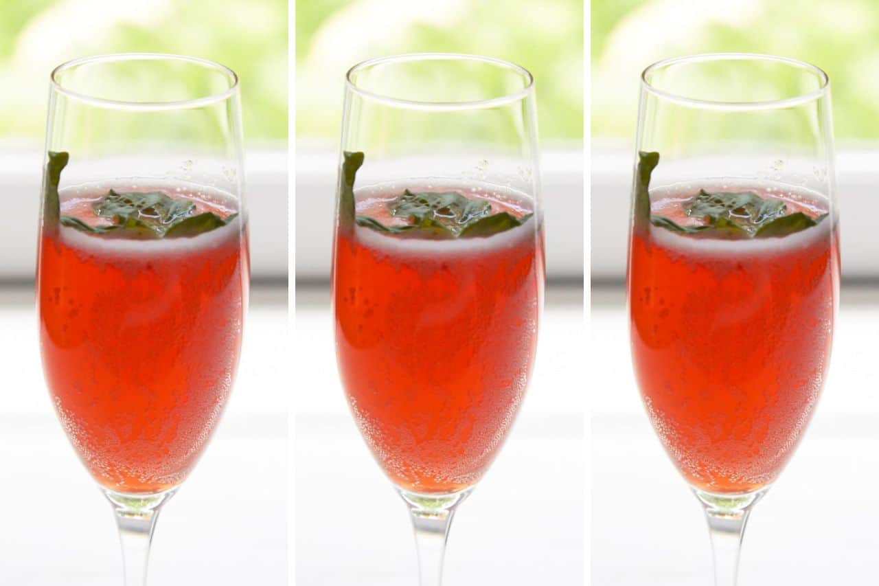 A strawberry prosecco cocktail in a champagne flute, garnished with a basil leaf.