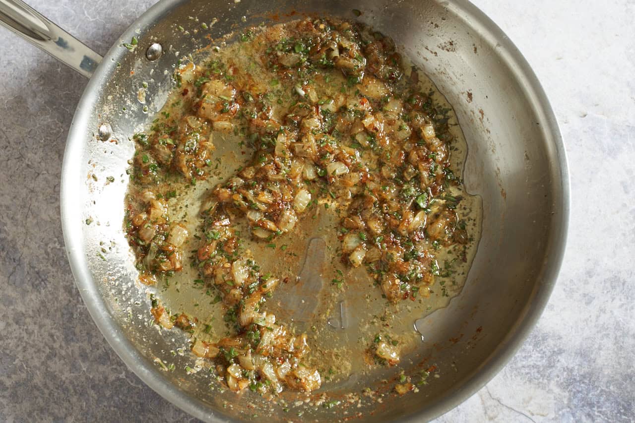 Onions, sage, rosemary, and crushed red pepper sautéed in butter in a skillet.