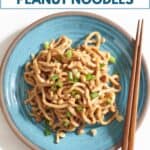 Spicy peanut noodles on a blue plate topped with chopped peanuts and scallions, with chopsticks on the side.