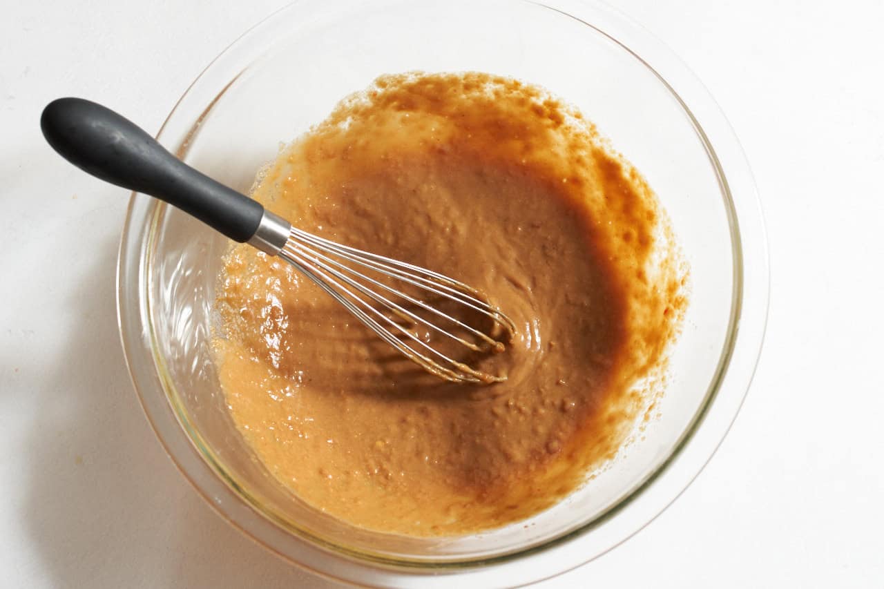 Finished spicy peanut sauce for noodles in a glass bowl.