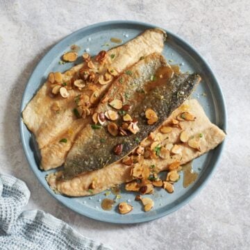 Trout amandine on a blue plate, a blue napkin is in the bottom left.