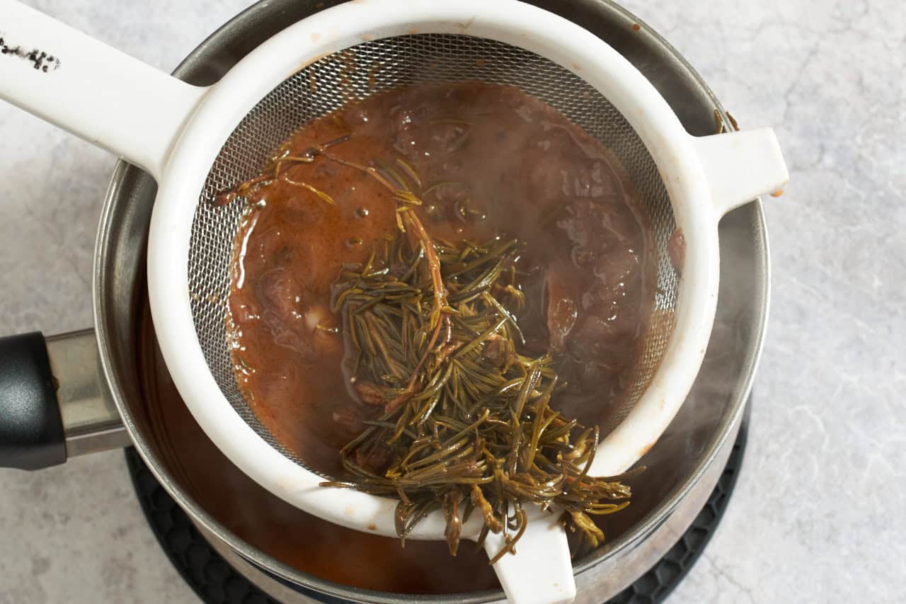 Red wine sauce for braised lamb shanks being strained into a sauce pan.