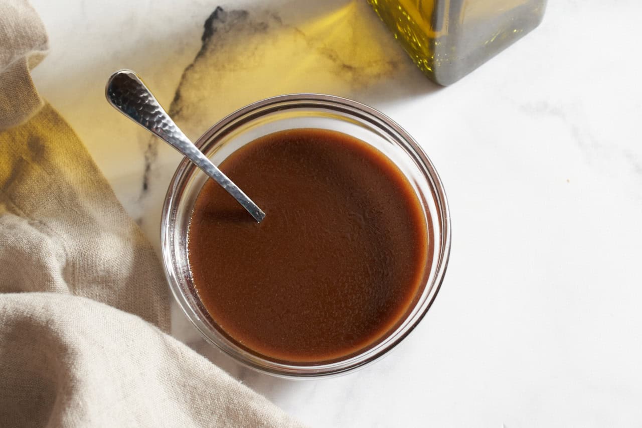 A small bowl of dijon balsamic vinaigrette with a spoon in it.