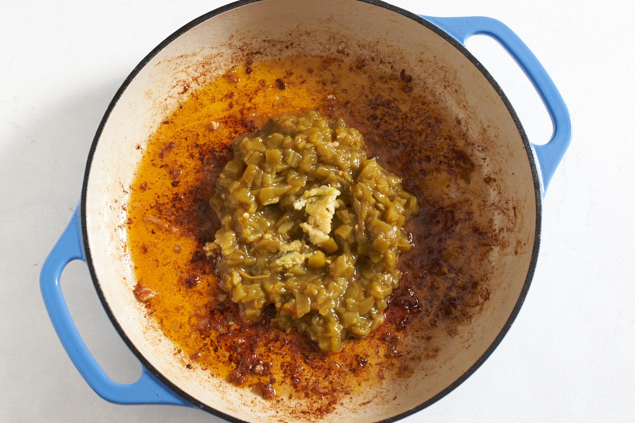 Green chiles and garlic in a pan with blue handles.