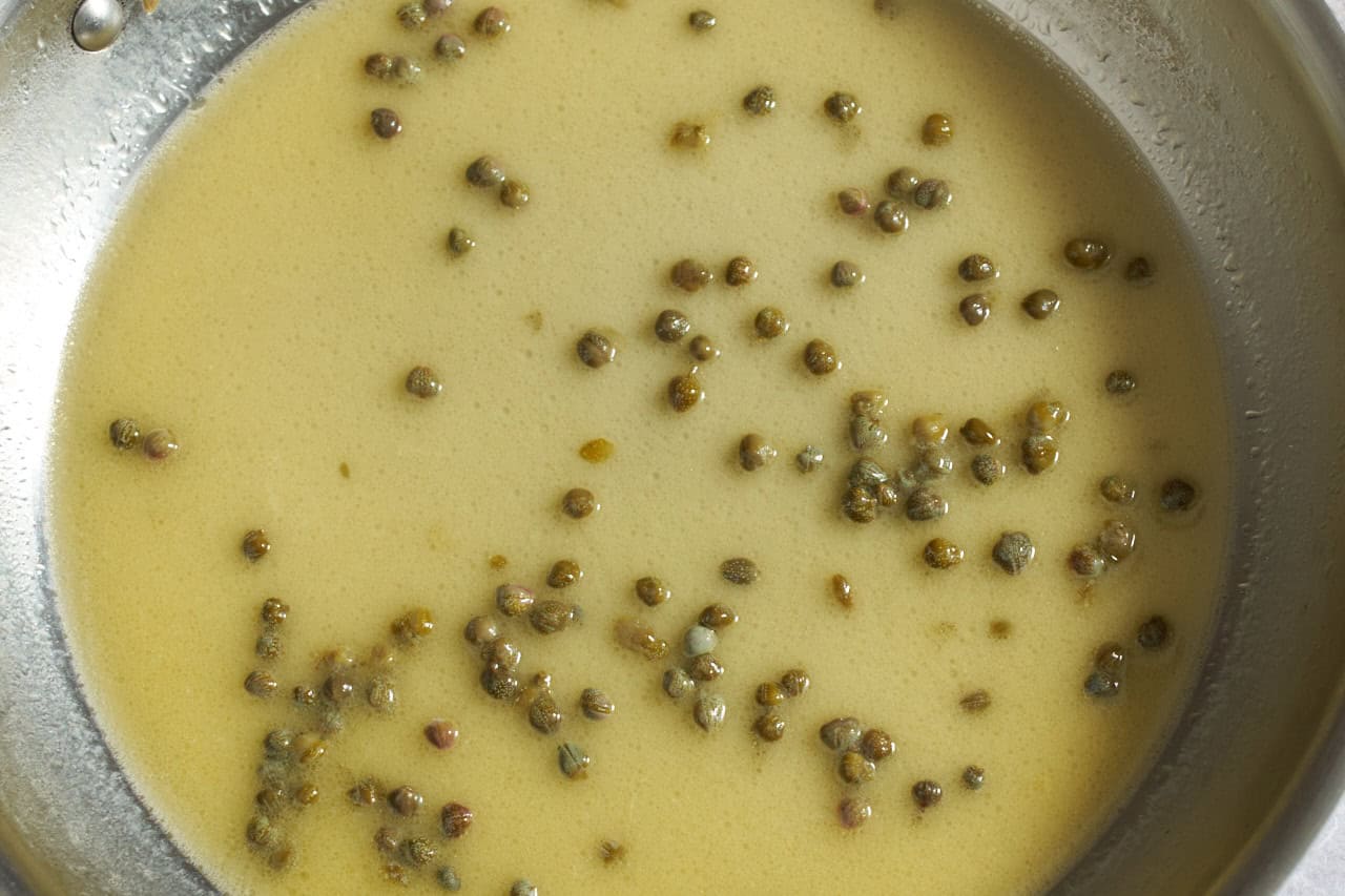 Lemon, butter, caper sauce in a skillet.