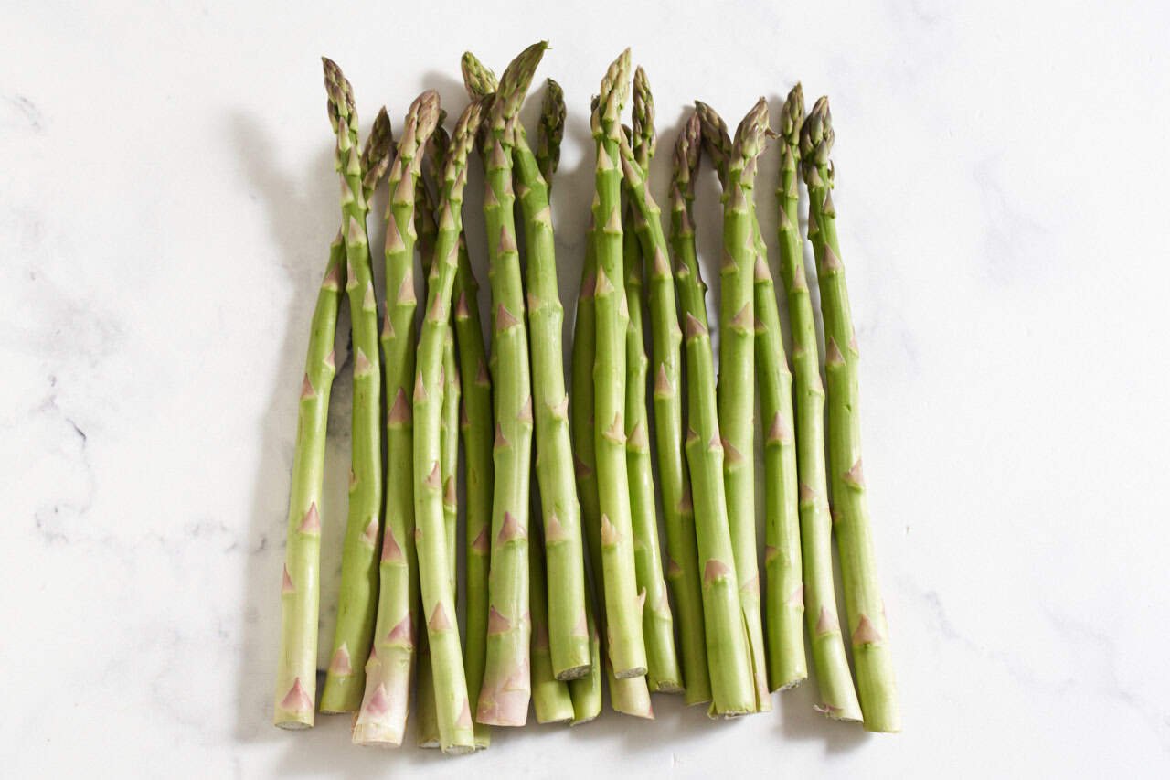 Several asparagus spears on a marble surface.