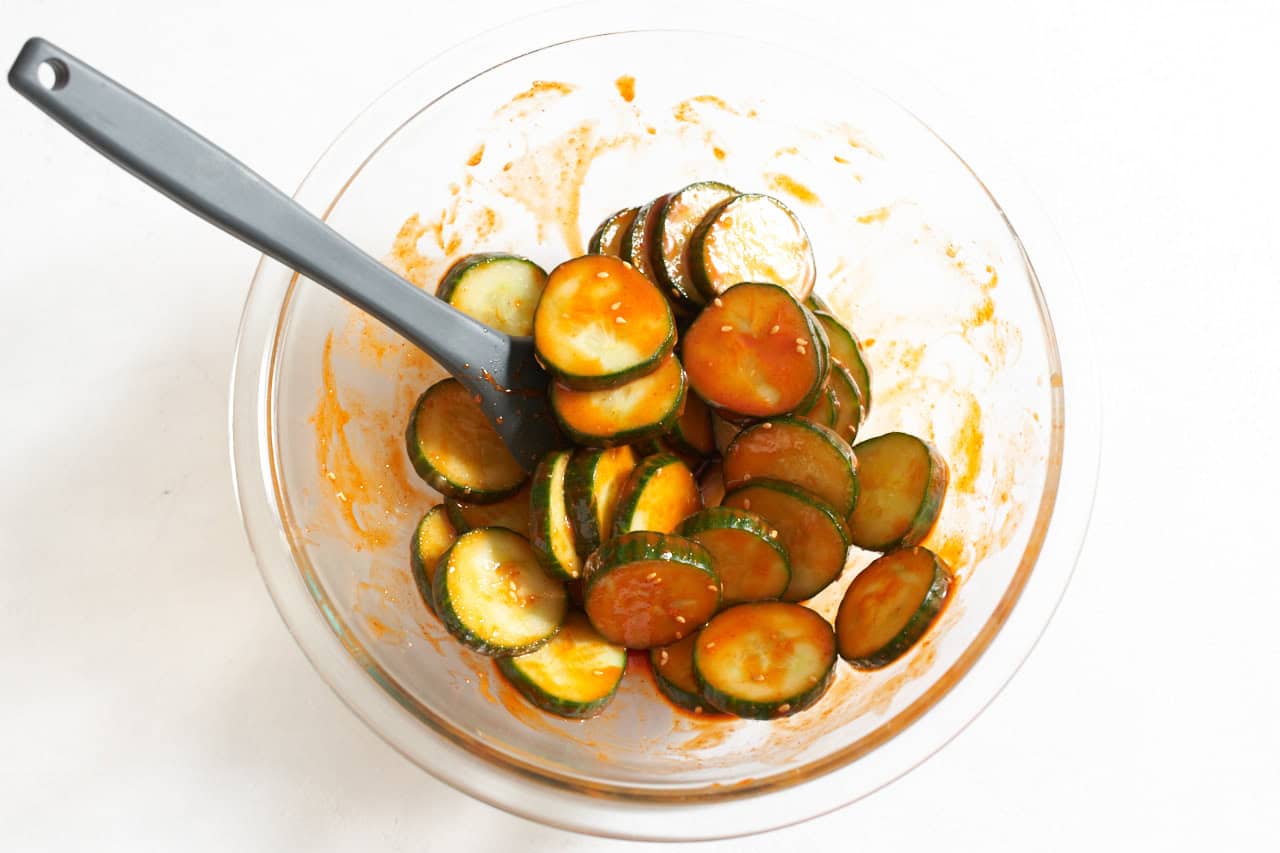 A bowl of cucumber slices tossed in a gochujang sauce.